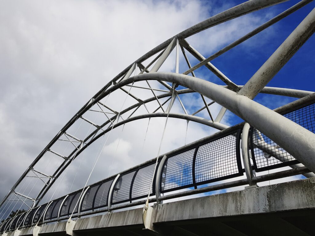 Modern structural steel arch bridge with walkway and connection detailing for infrastructure project