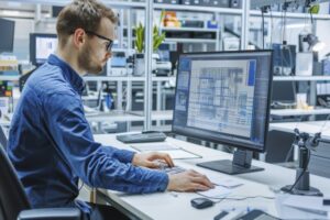 Structural steel engineer reviewing 3D detailing drawings on computer in an engineering workspace