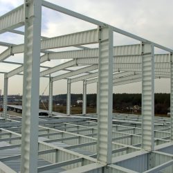 The metal frame of the warehouse building made of SIN beams is painted white. Construction of corrugated I-beams.